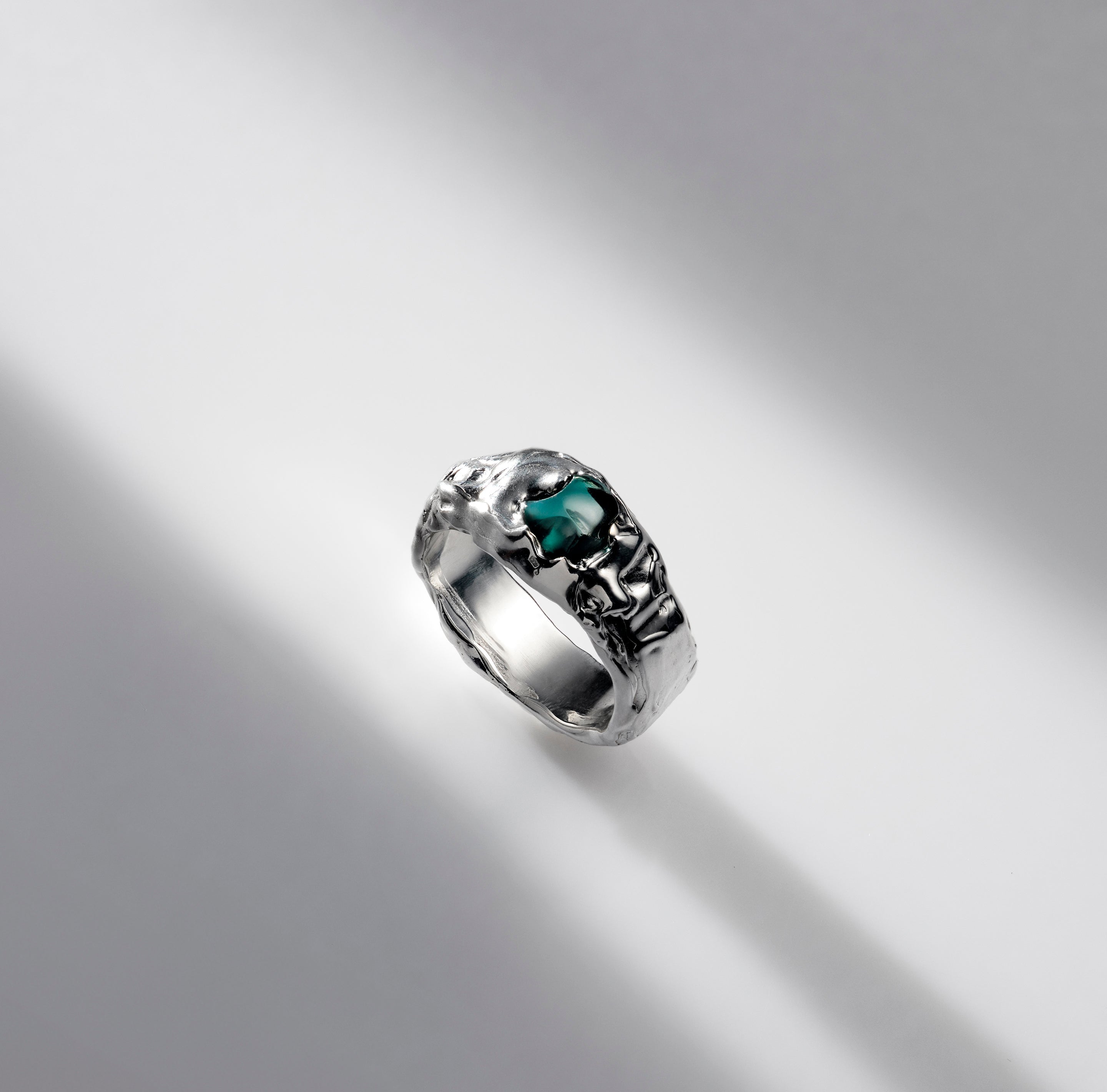 Silver ring with a green gemstone on a gray background